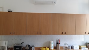 Une cuisine avec des meubles de rangement en bois, une machine à café, un grille-pain, une bouilloire et divers ustensiles de cuisine posés sur le plan de travail.