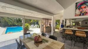 A spacious dining area with a view of a swimming pool and outdoor seating.