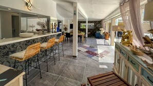 A spacious kitchen with a marble countertop, bar stools, and a dining area with a patterned rug.