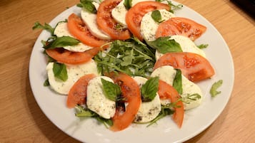 A plate of Caprese salad with tomatoes, mozzarella, and basil on a wooden table.