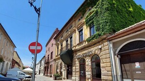 Una calle con un edificio cubierto de hiedra, una señal de prohibido el paso y coches aparcados.
