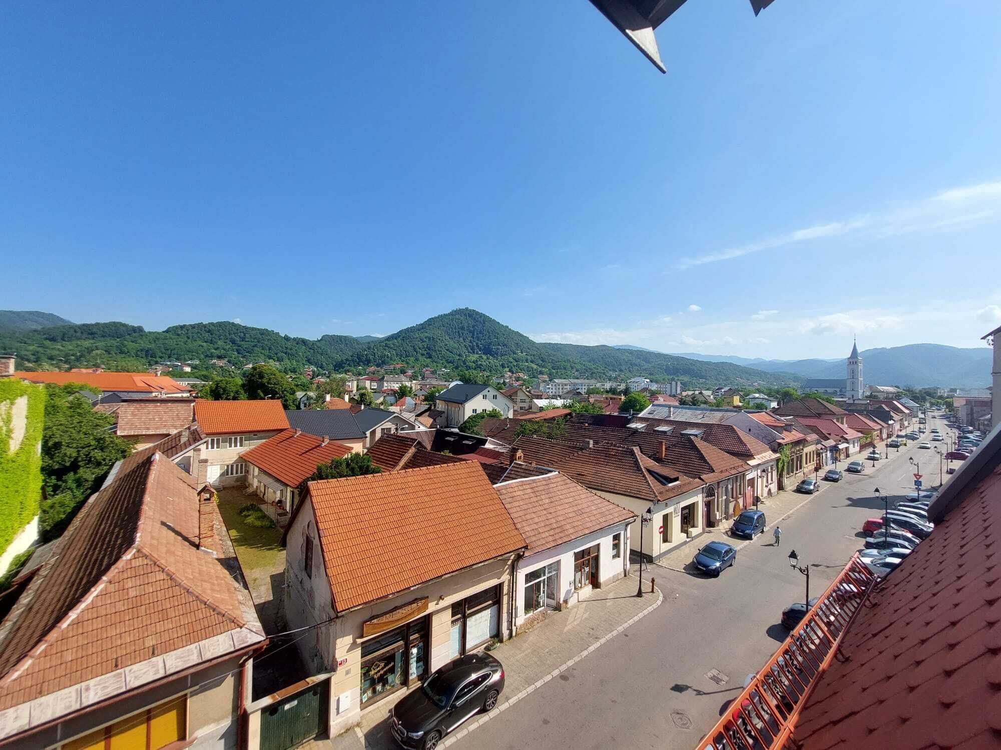 A town with red-tiled roofs, a main street, and a mountain in the background.