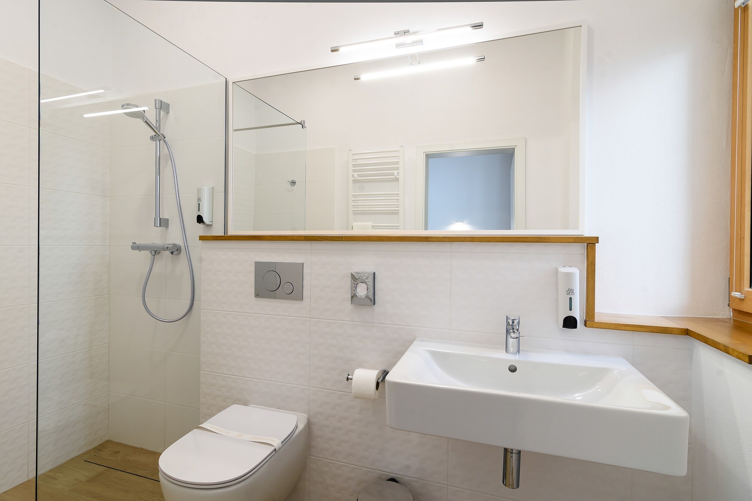 Ein modernes Badezimmer mit Duschkabine aus Glas, einem weißen Waschbecken und einer Toilette.