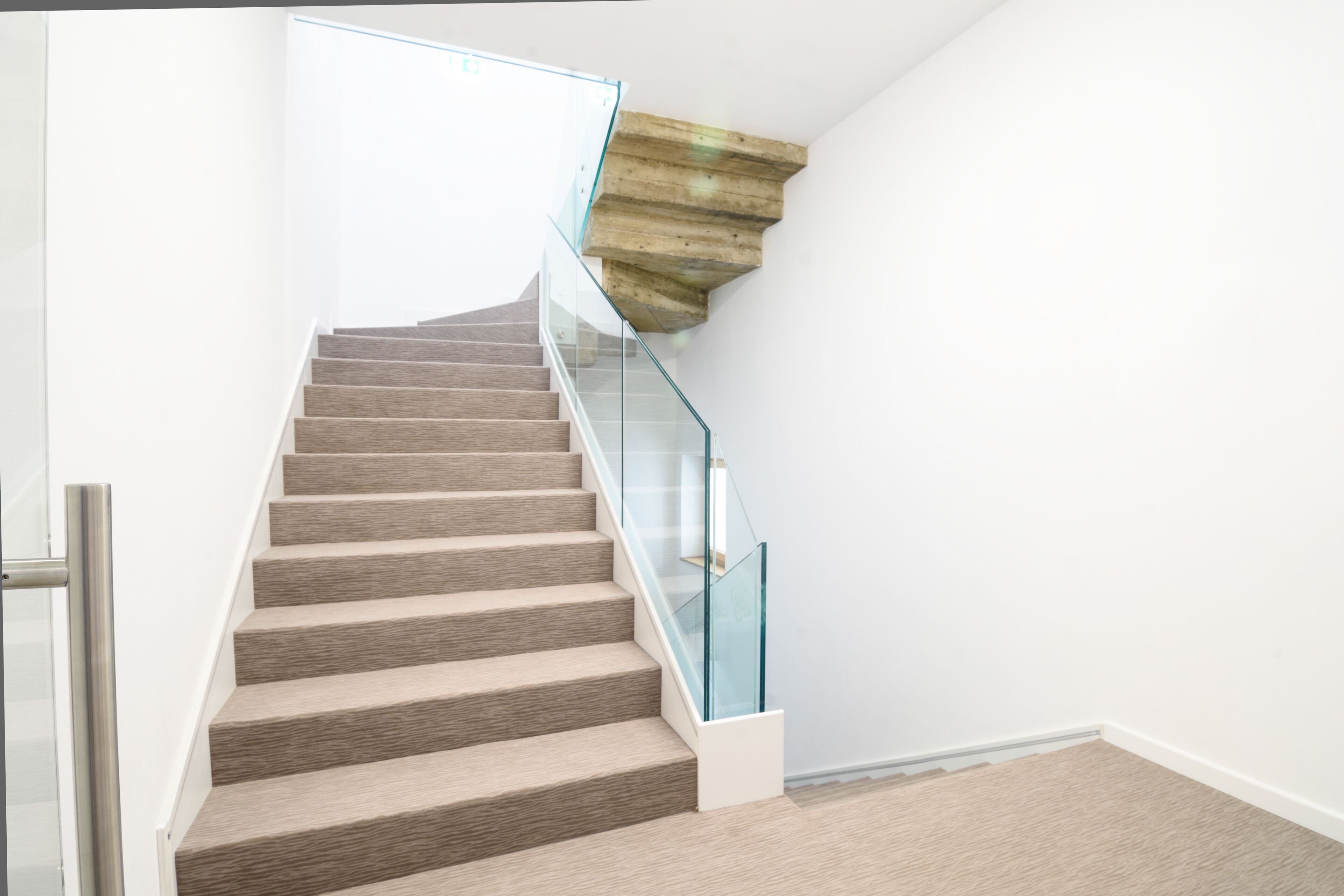 Una escalera moderna con barandillas de vidrio y un panel de acento de madera.