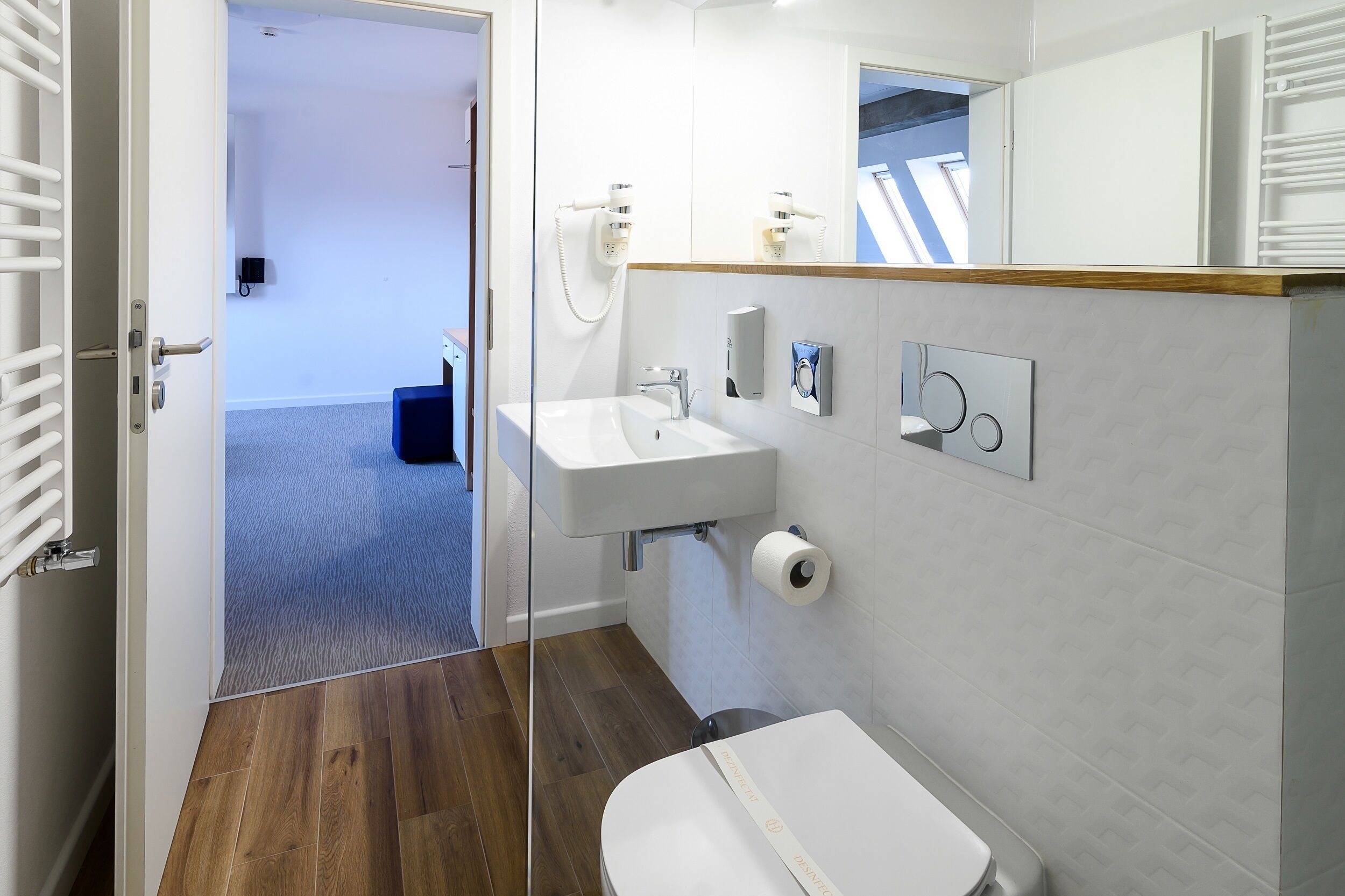A modern bathroom with a white sink, a toilet, and a shower area.