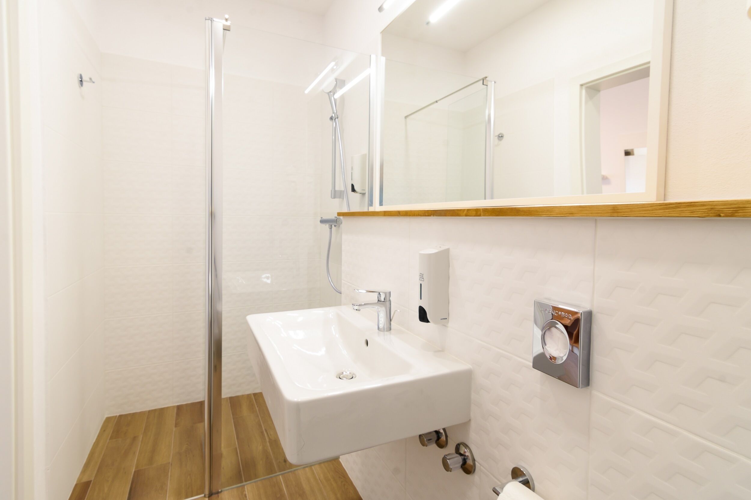 Un baño moderno con cabina de ducha de vidrio, un lavabo blanco y un espejo sobre él.