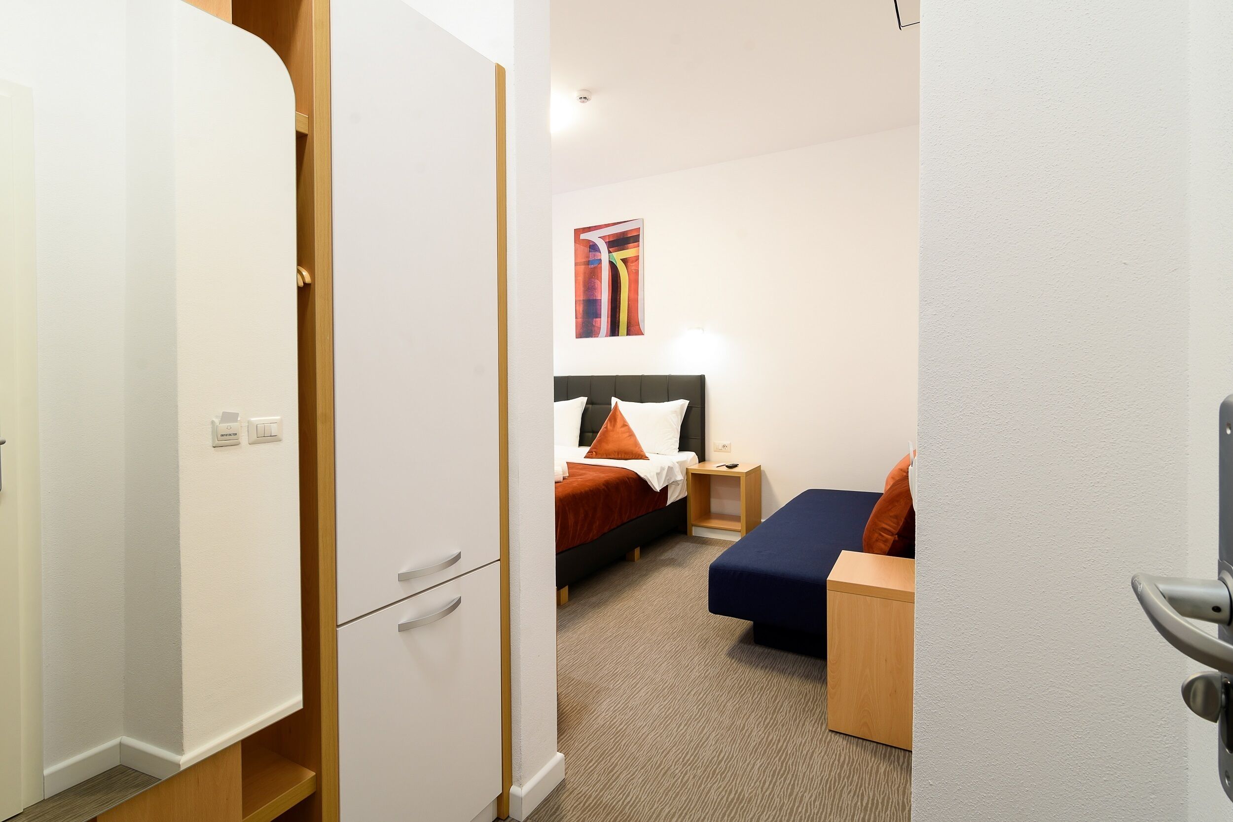Una habitación de hotel con una cama, un escritorio y un armario.