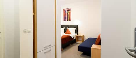 Una habitación de hotel con una cama, un escritorio y un armario.
