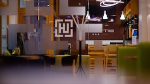 Una moderna zona de recepción de hotel con un separador de vidrio, muebles de madera e iluminación contemporánea.