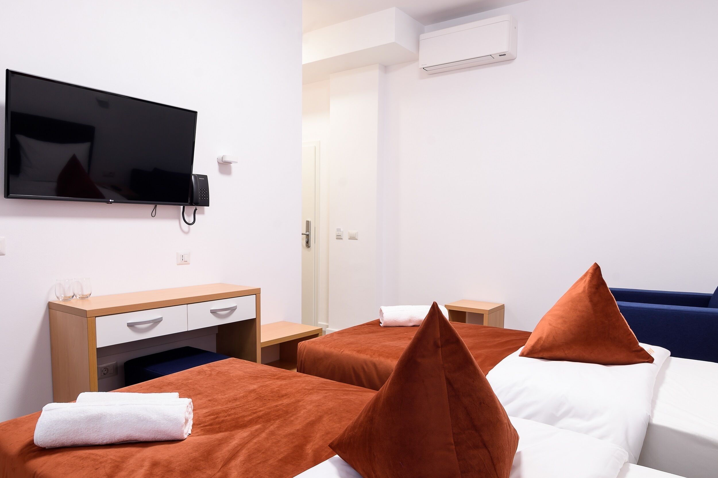 Hotellihuone, jossa on kaksi sänkyä, työpöytä, televisio ja ovi.