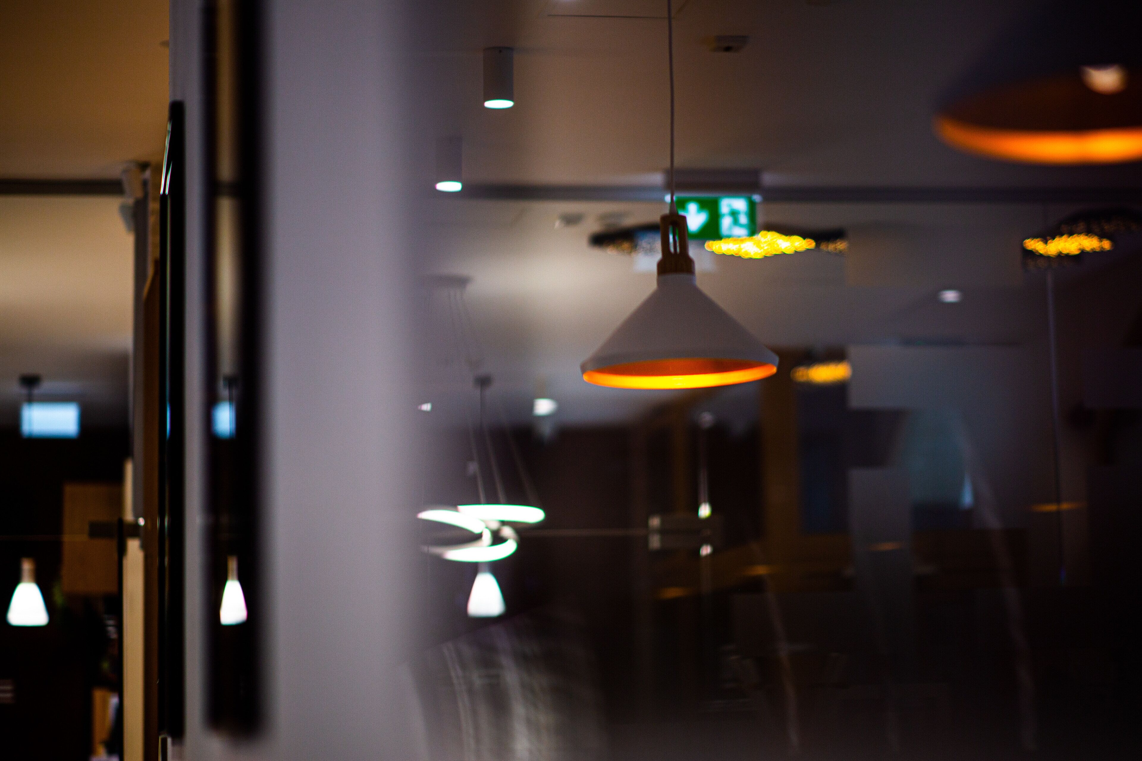 A modern interior with pendant lighting and a visible exit sign.