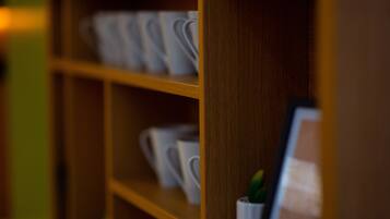 A wooden shelf with white cups and a small potted plant.