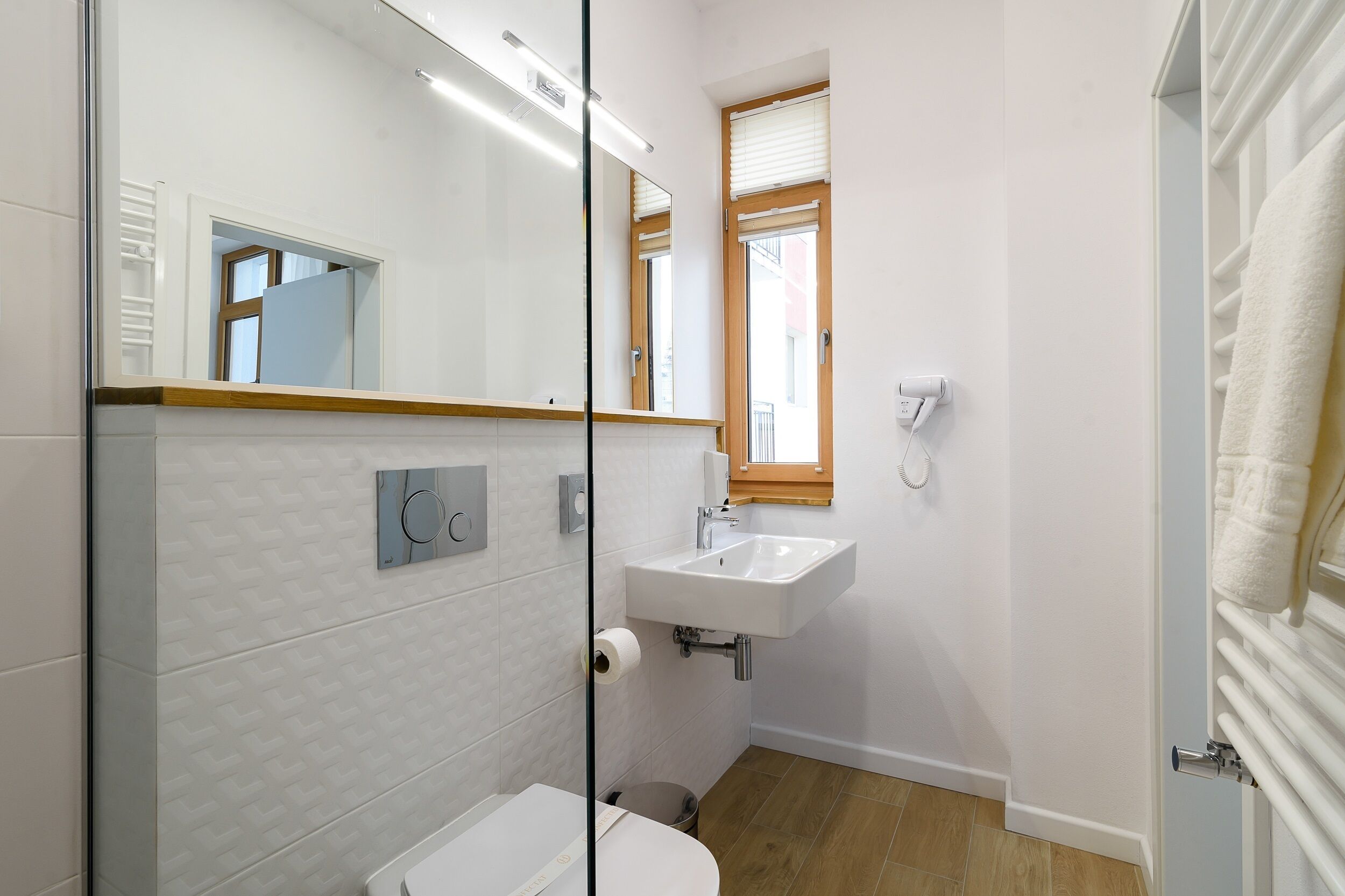 Un baño moderno con un lavabo, espejo y retrete blancos.