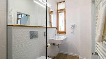 Un baño moderno con un lavabo, espejo y retrete blancos.