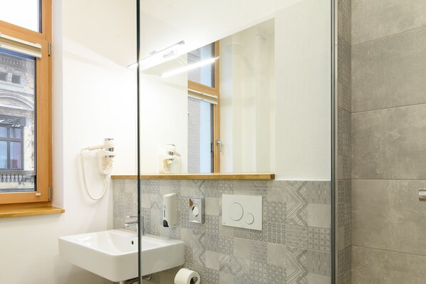 A bathroom with a white sink, a mirror, a window, and patterned tiles. - Hotel Urban (Baia Mare)