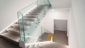 Una escalera moderna con barandillas de cristal y peldaños de madera.