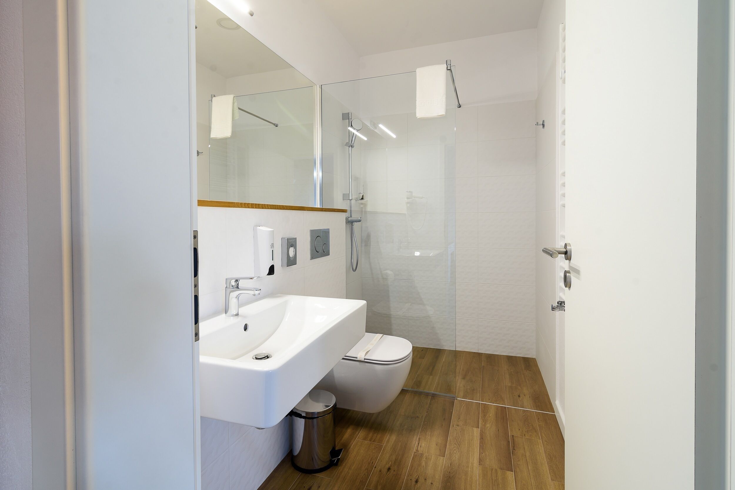 Une salle de bain moderne avec un lavabo blanc, des toilettes et une douche à parois de verre.