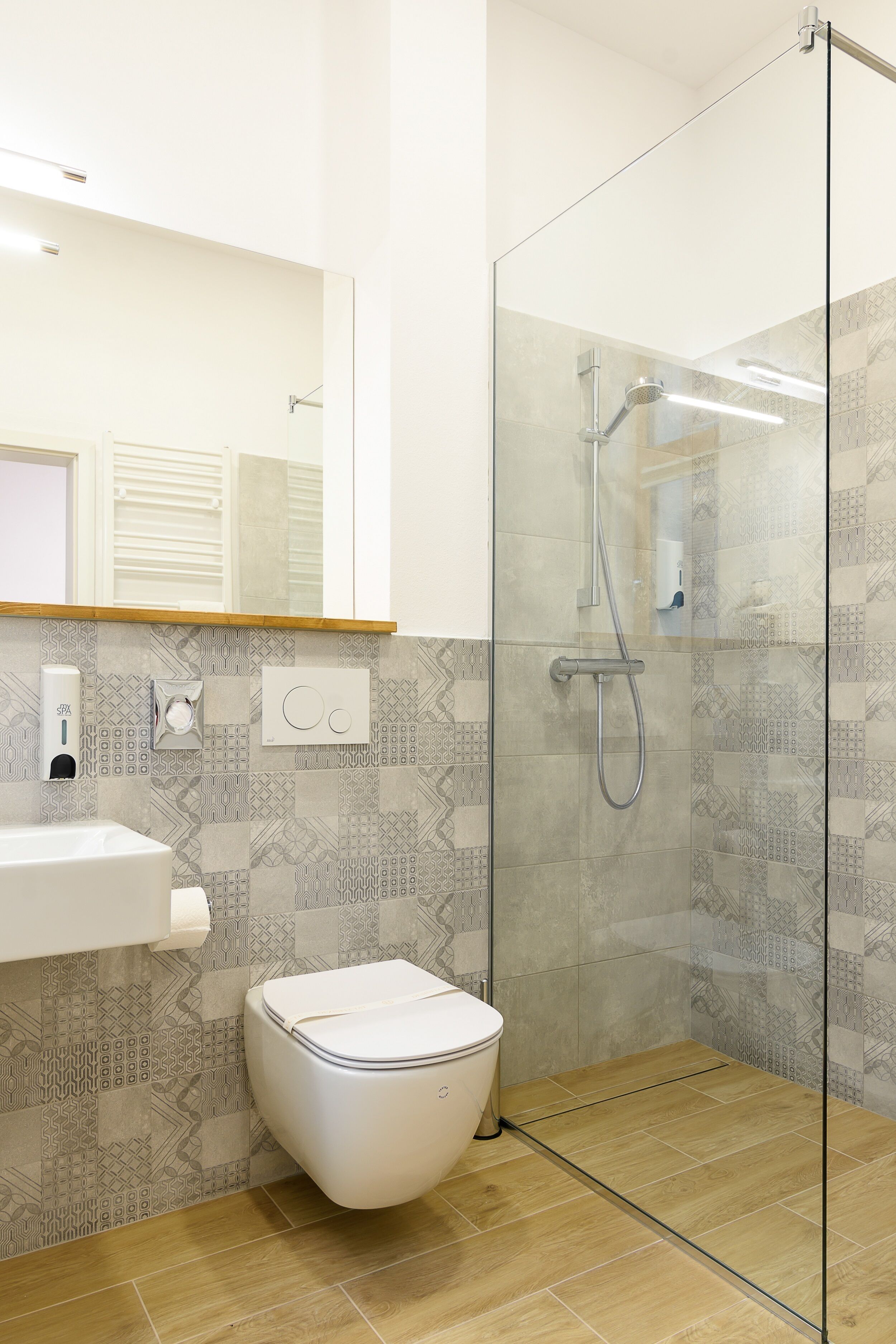 A modern bathroom with a glass shower enclosure, a toilet, and a sink with a soap dispenser.
