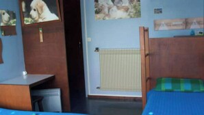 Et værelse med to senge, et skrivebord, en radiator og en dør.