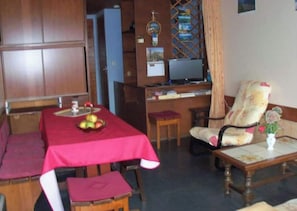 Un comedor con mantel rojo, frutero y aparador de madera.