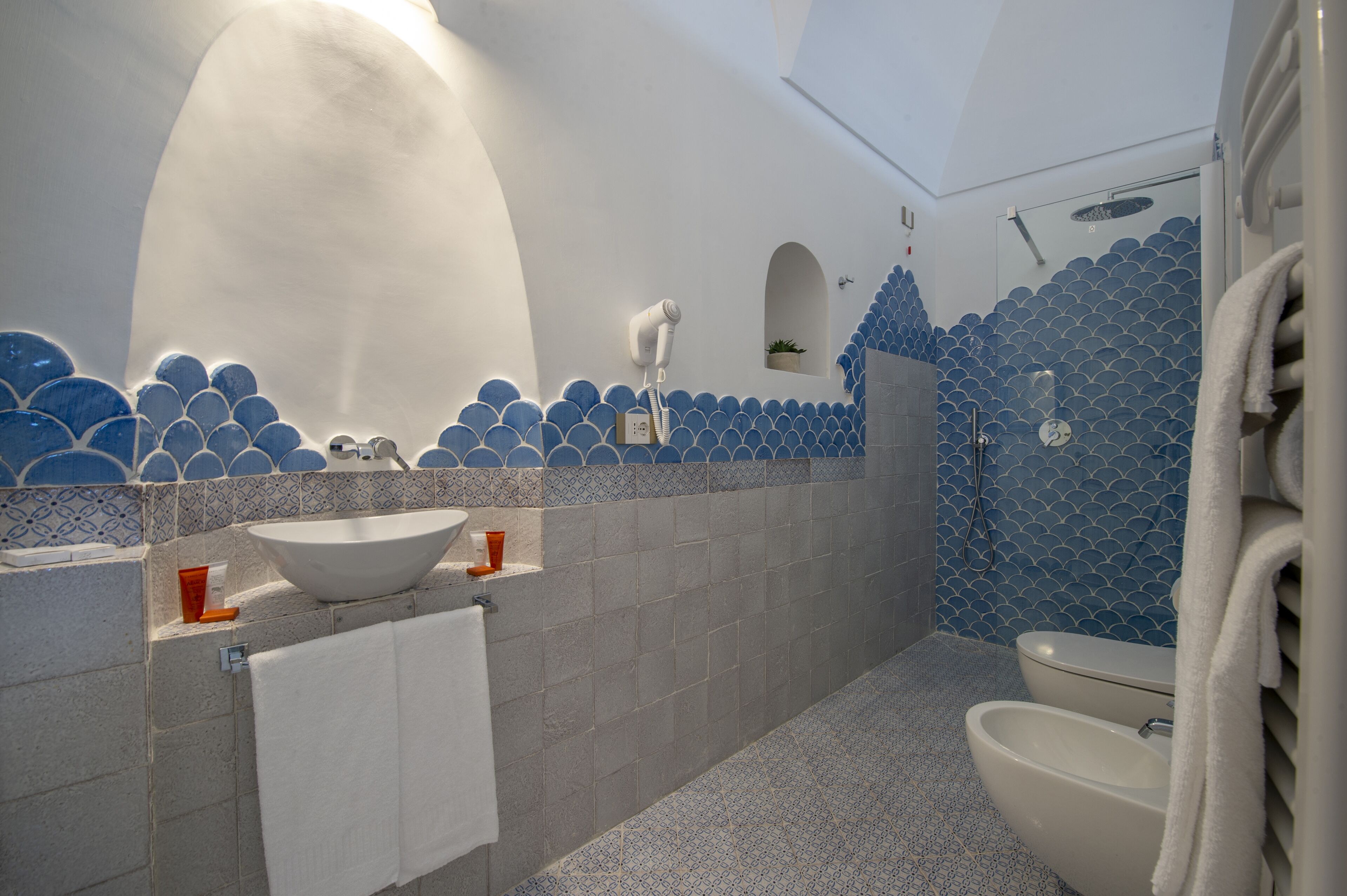 A bathroom with a large white sink, a toilet, and a shower area.