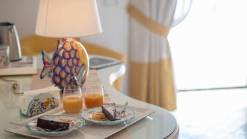 A breakfast table with a pineapple-shaped lamp, a glass of orange juice, and plates of food including a slice of cake and a pastry.