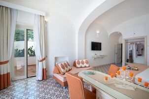 Una habitación de hotel con un conjunto de sofás, una mesa de comedor con velas y un televisor.