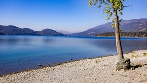 Una vista limpida di un lago con una riva rocciosa e un albero sullo sfondo.