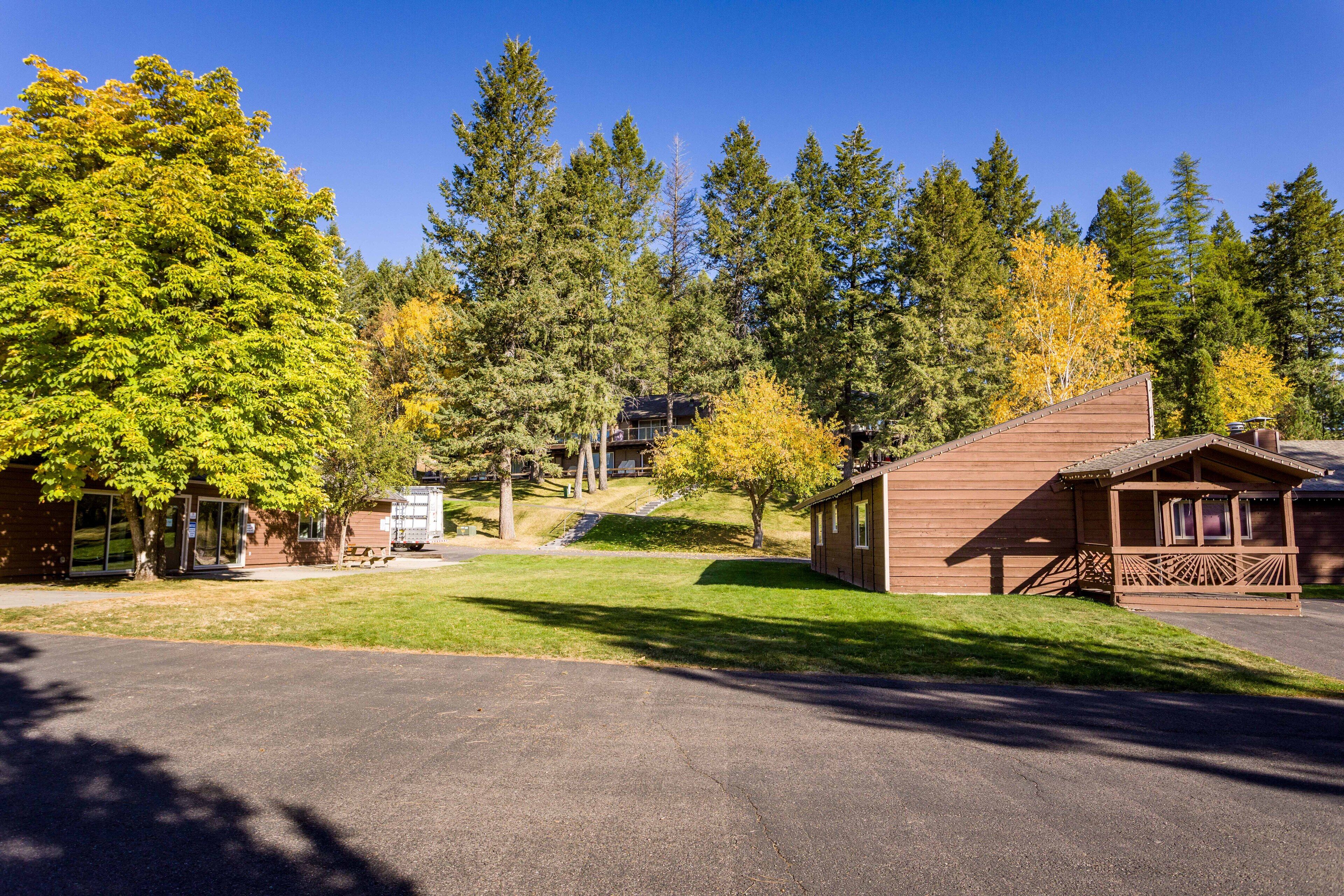 A lodge with a wooden exterior, a covered porch, and a parking area.