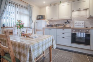 A kitchen with a table set for dining, a microwave, a toaster, and a refrigerator.