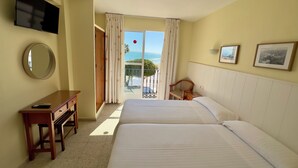 Une chambre d’hôtel avec deux lits, un bureau, une télévision et un balcon avec vue.