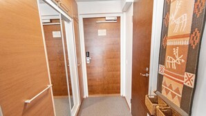 Un pasillo con puertas de madera, suelo alfombrado y una cesta tejida a la derecha.