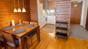 Una cocina moderna con paredes de madera, un área de comedor con una mesa y sillas de madera, y una pequeña isla de cocina.