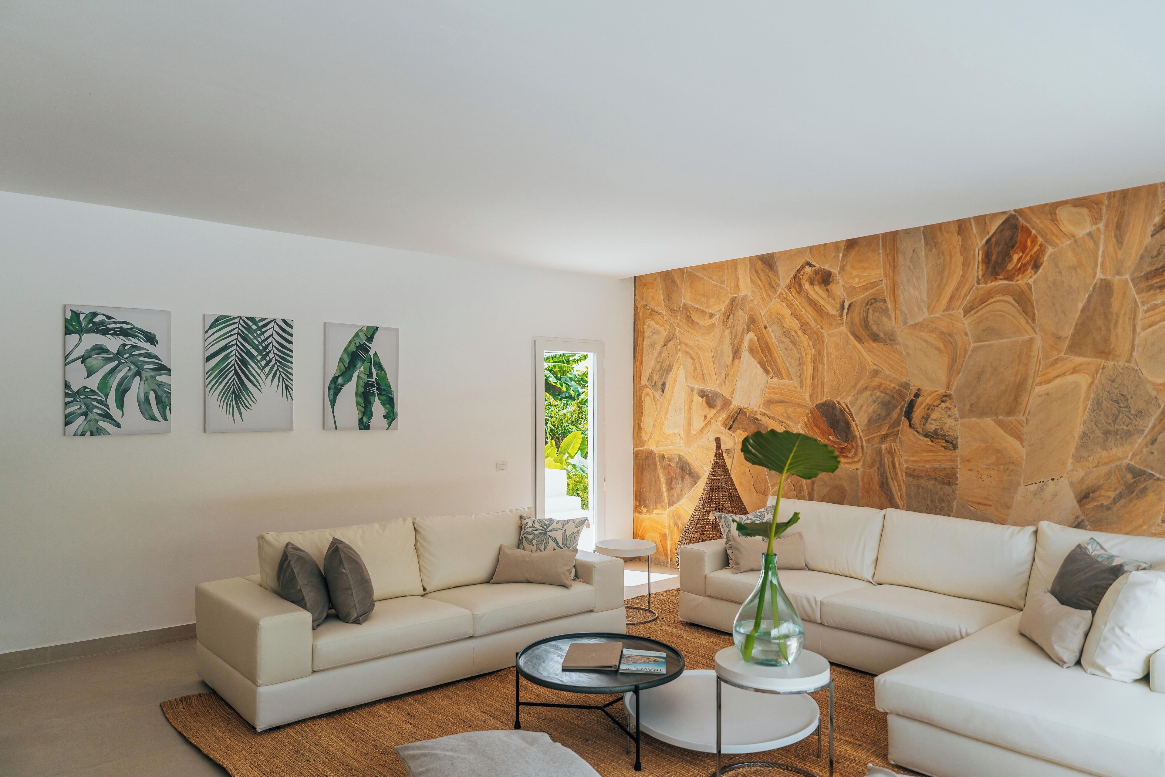 A modern living room with a white sofa, a coffee table, and a stone wall.