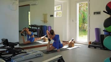 A gym with exercise equipment, a mirror, and a door leading to a garden.
