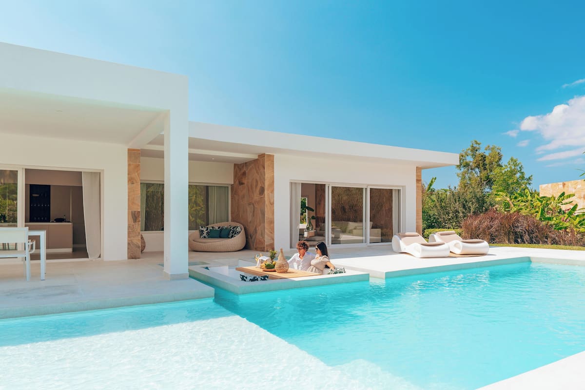 Ein modernes Haus mit Schwimmbad, Sitzgelegenheiten im Freien und einer Terrassenfläche.