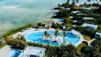 A resort with a large pool, palm trees, and a view of the ocean.
