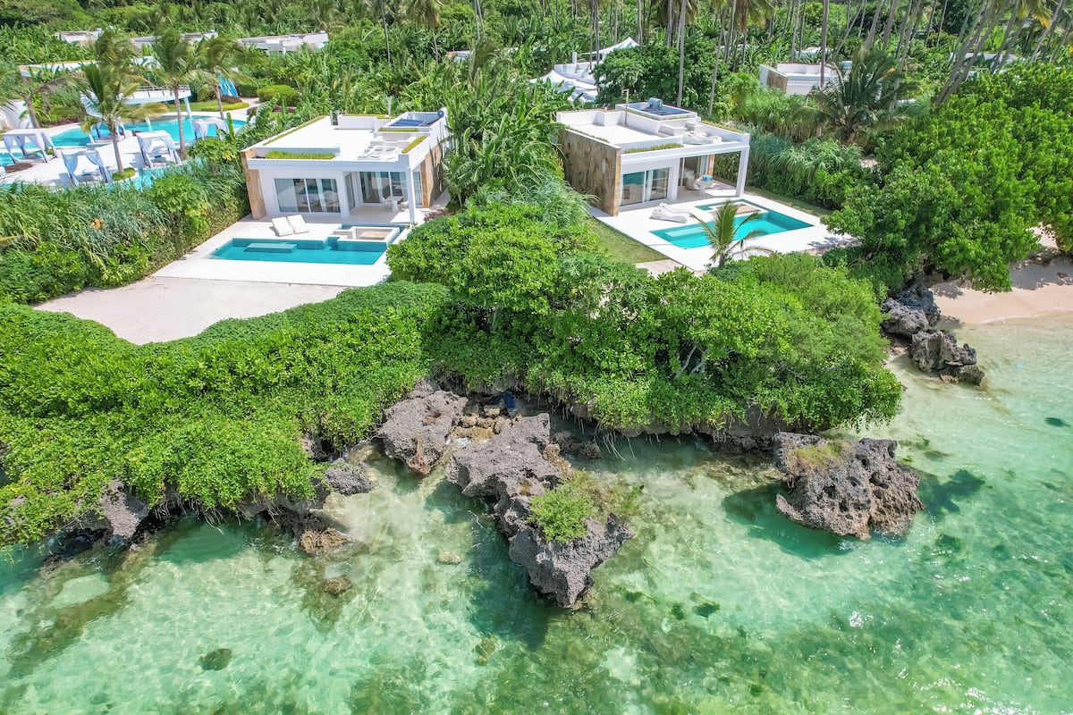 Ein Resort mit mehreren Schwimmbecken, üppiger Vegetation und einem Strand.