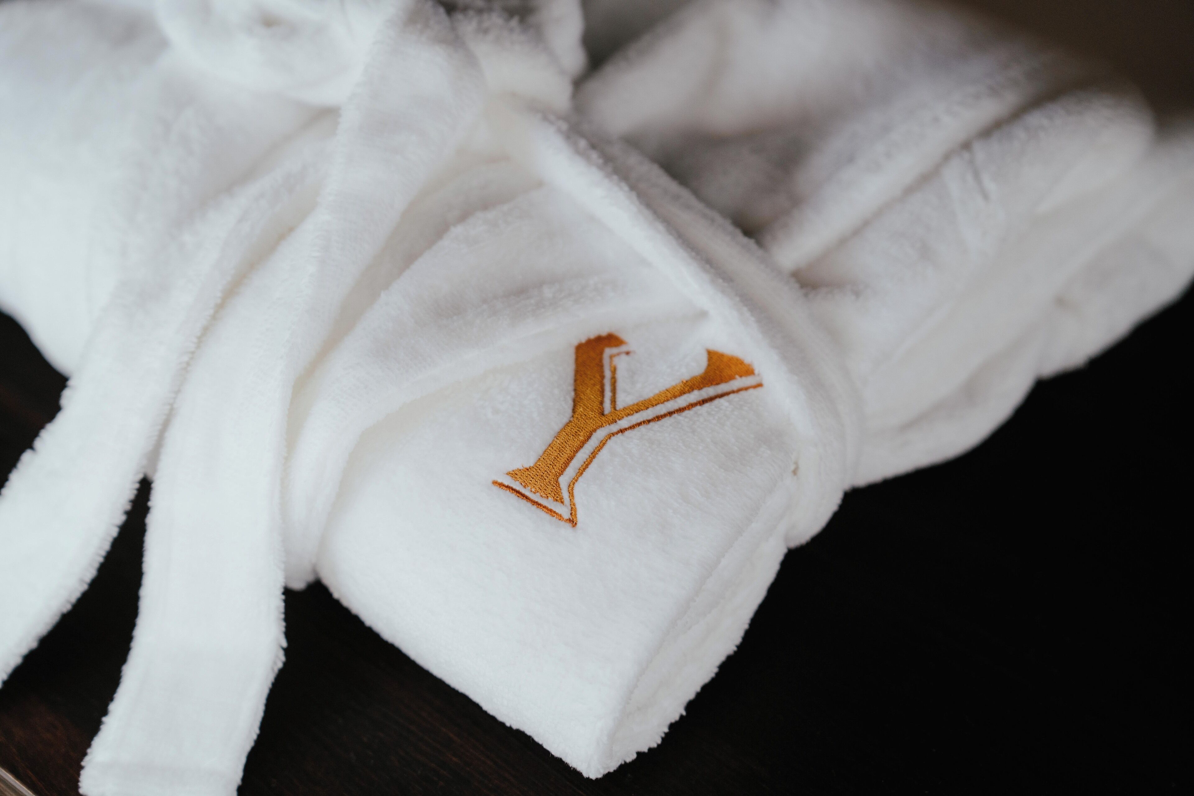 Una bata blanca con un logotipo bordado en oro.