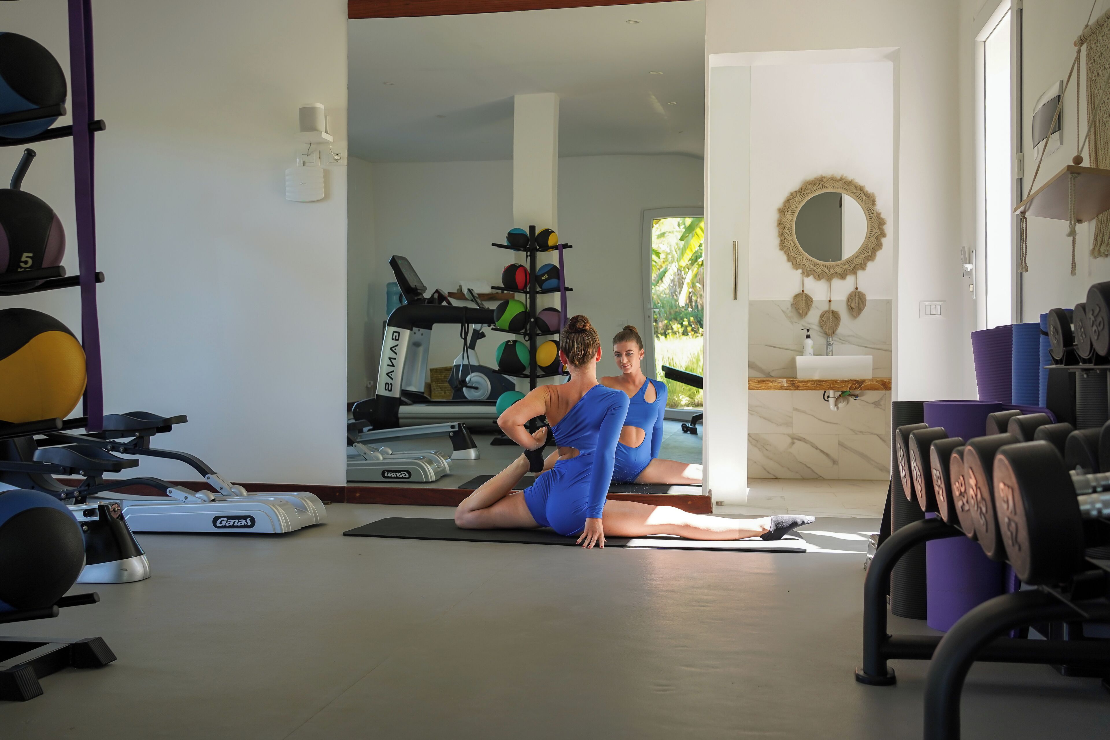 A gym with exercise equipment, a treadmill, and a mirror.