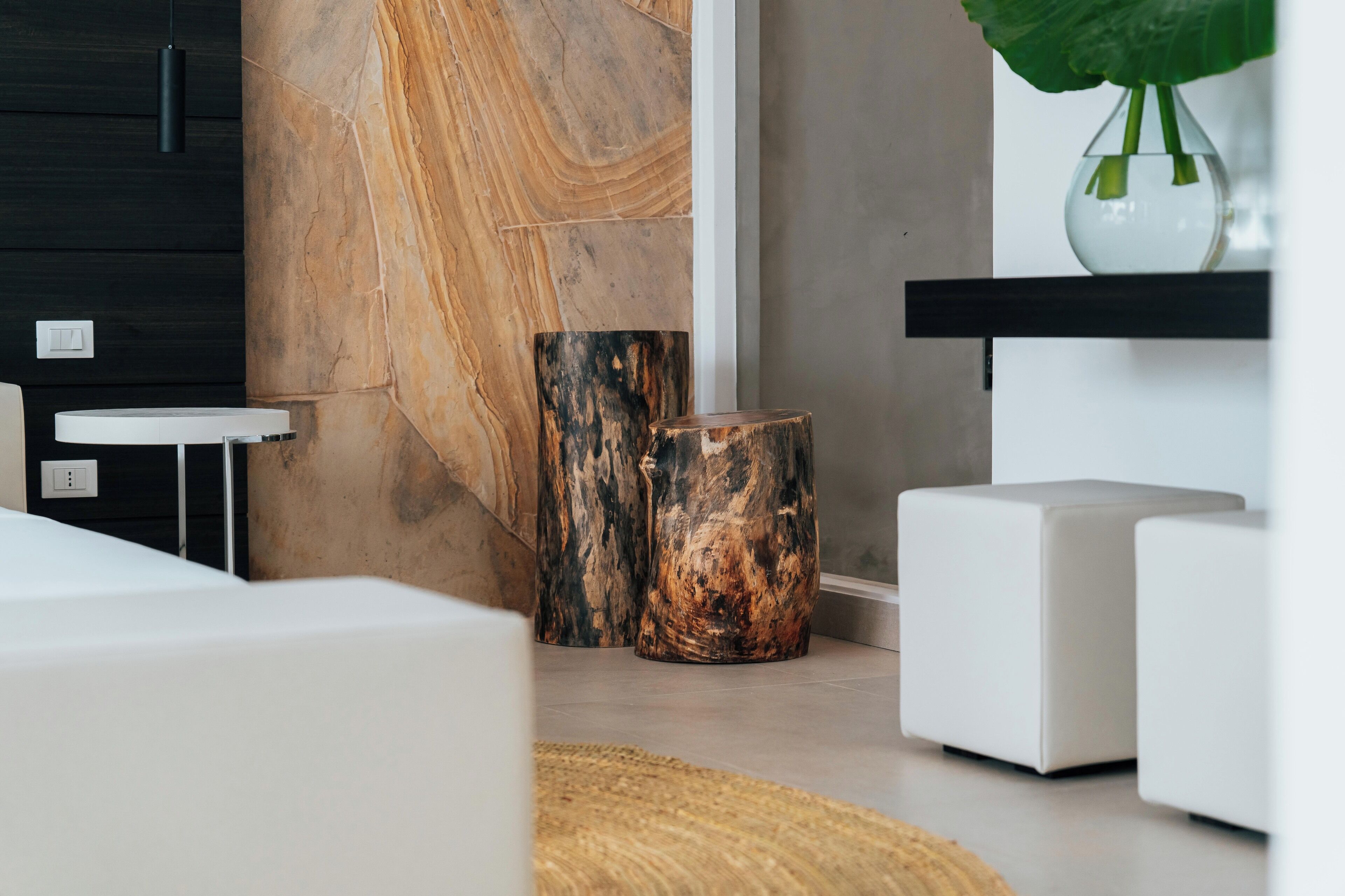 Un salon moderne avec un canapé blanc, une table ronde en bois et une grande plante dans un vase.