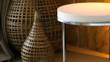 Una habitación con una mesa redonda blanca, dos grandes jarrones tejidos y una pared de madera con textura similar al mármol.