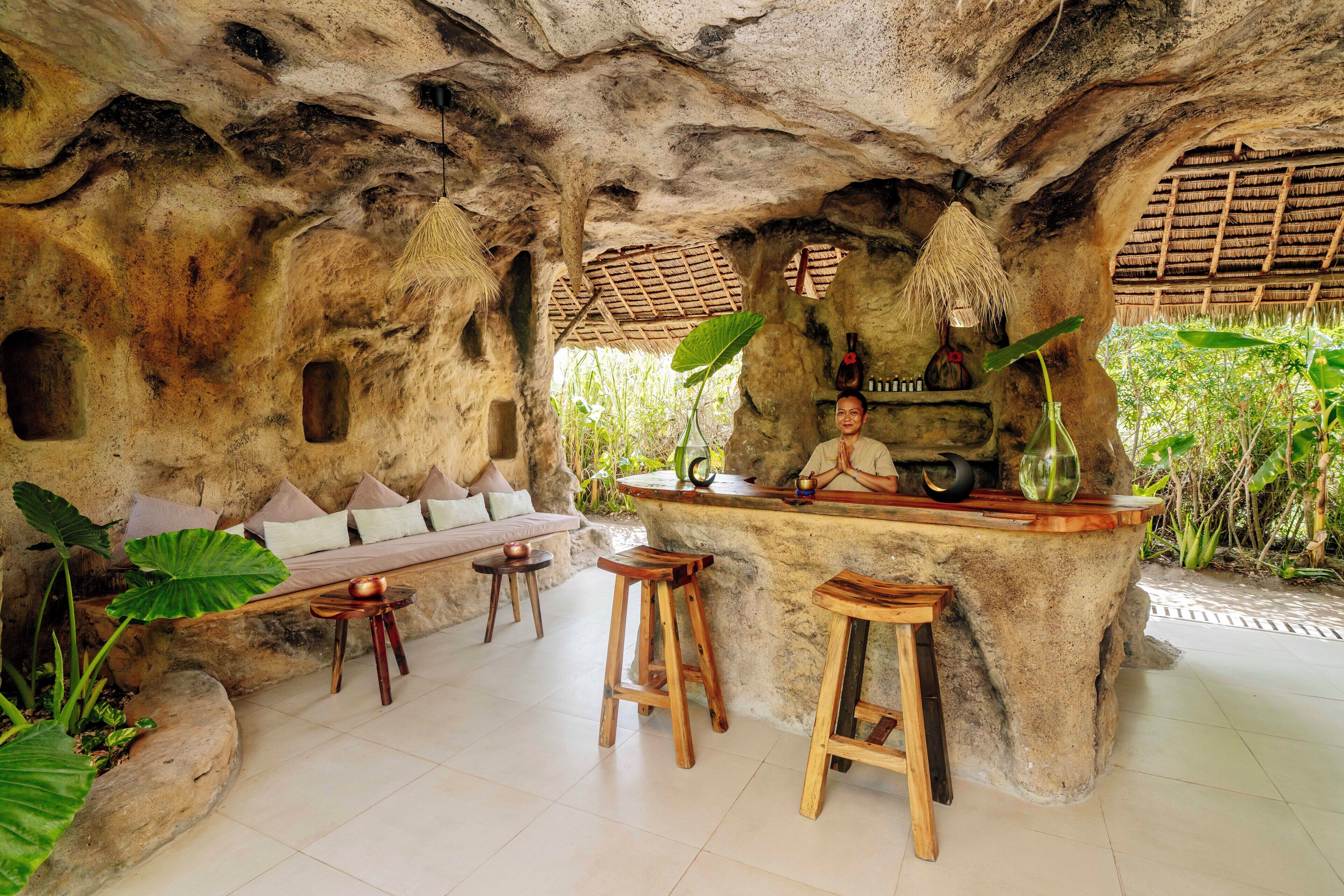 Un rústico espacio de bar con pared de piedra, taburetes de madera y un banco.