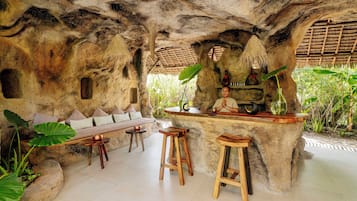 Un rústico espacio de bar con pared de piedra, taburetes de madera y un banco.