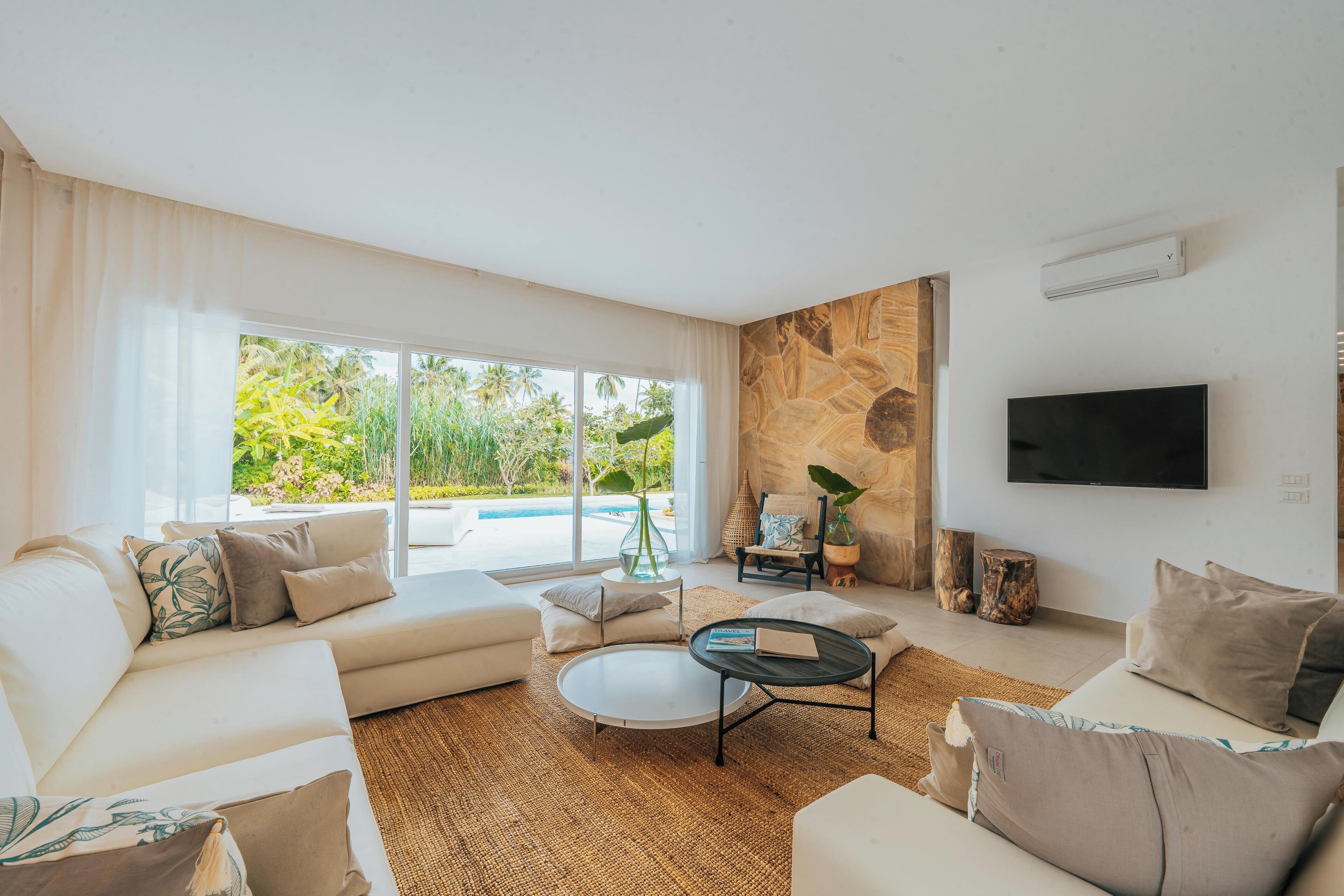 A modern living room with a large window, a flat-screen TV, and a stone accent wall.
