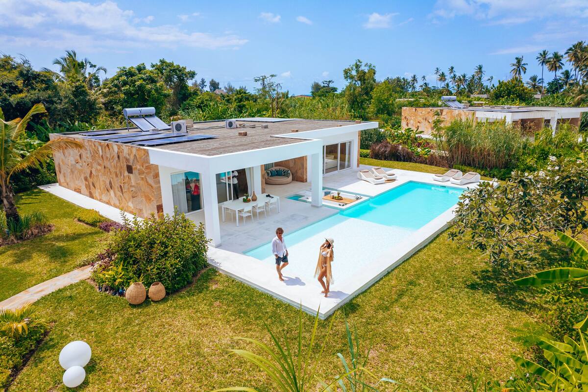 Ein modernes Haus mit Swimmingpool, Terrasse und üppiger Bepflanzung.