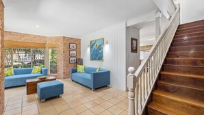 A living room with two blue sofas, a wooden coffee table, and a staircase. - Palm Beach House - Red Rock location (Red Rock)