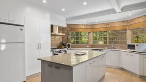 A modern kitchen with white cabinetry, a granite countertop, a built-in stove, and a microwave. - Palm Beach House - Red Rock location (Red Rock)