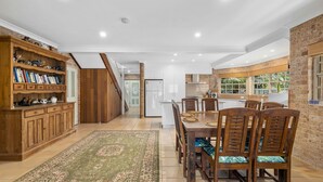 A spacious kitchen with a dining area, wooden cabinets, and a view of the outdoors. - Palm Beach House - Red Rock location (Red Rock)