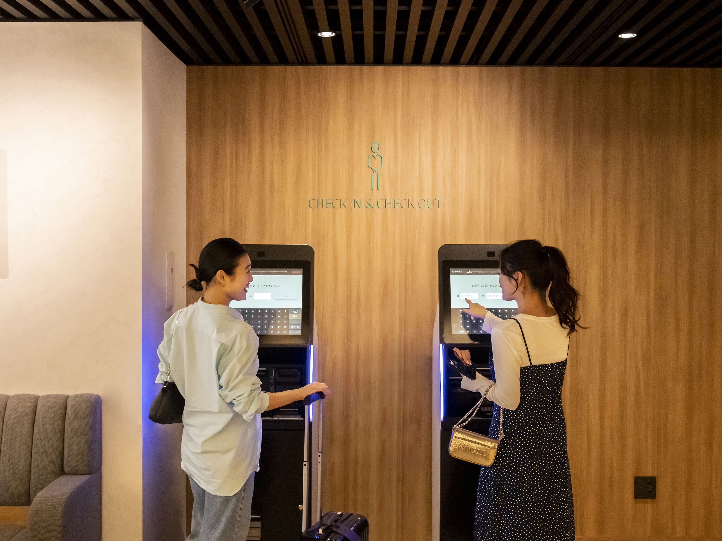 Two individuals using a self-service kiosk for check-in and check-out at a hotel.